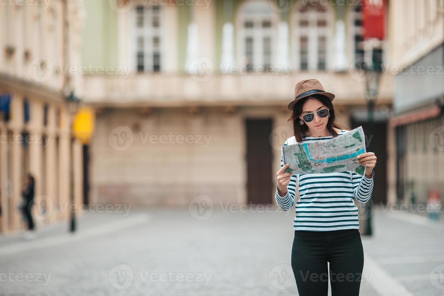 heureuse jeune femme avec un plan de la ville en ville. femme touristique de voyage avec carte à l'extérieur pendant les vacances en europe. photo