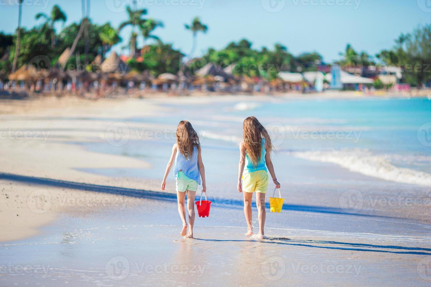 vue arrière de petites belles filles marchant sur le bord de mer tropical photo