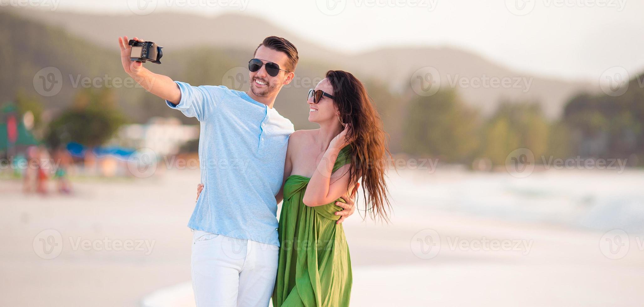 couple heureux prenant une photo de selfie sur la plage blanche.