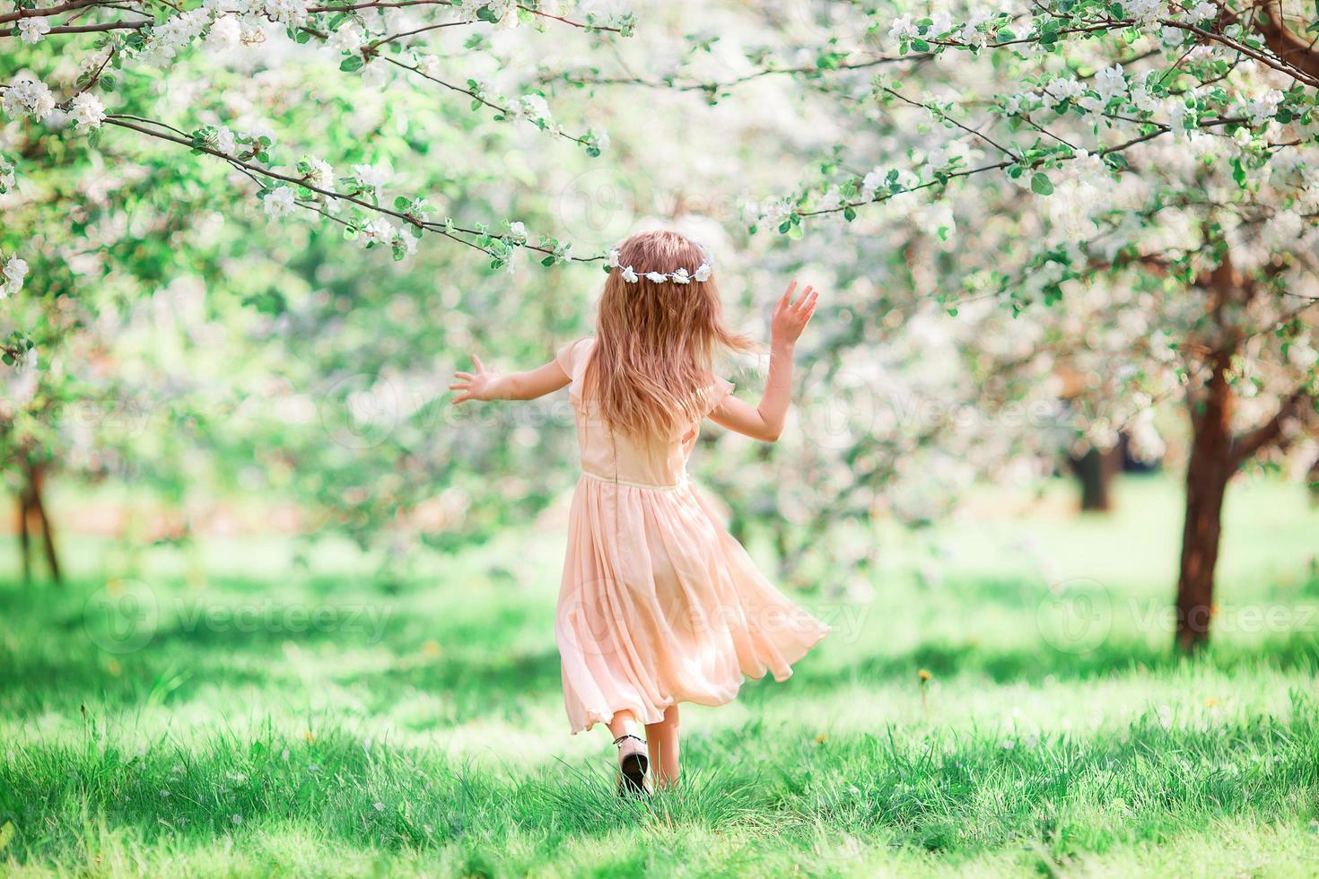 adorable petite fille dans un jardin de cerisiers en fleurs à l'extérieur photo