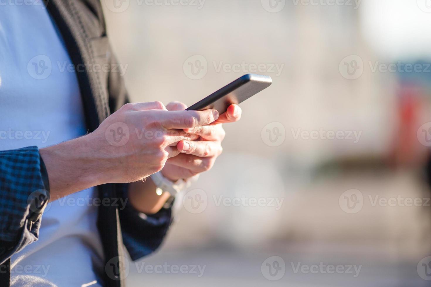 gros plan de mains masculines tient un téléphone portable à l'extérieur dans la rue. homme utilisant un smartphone mobile. photo