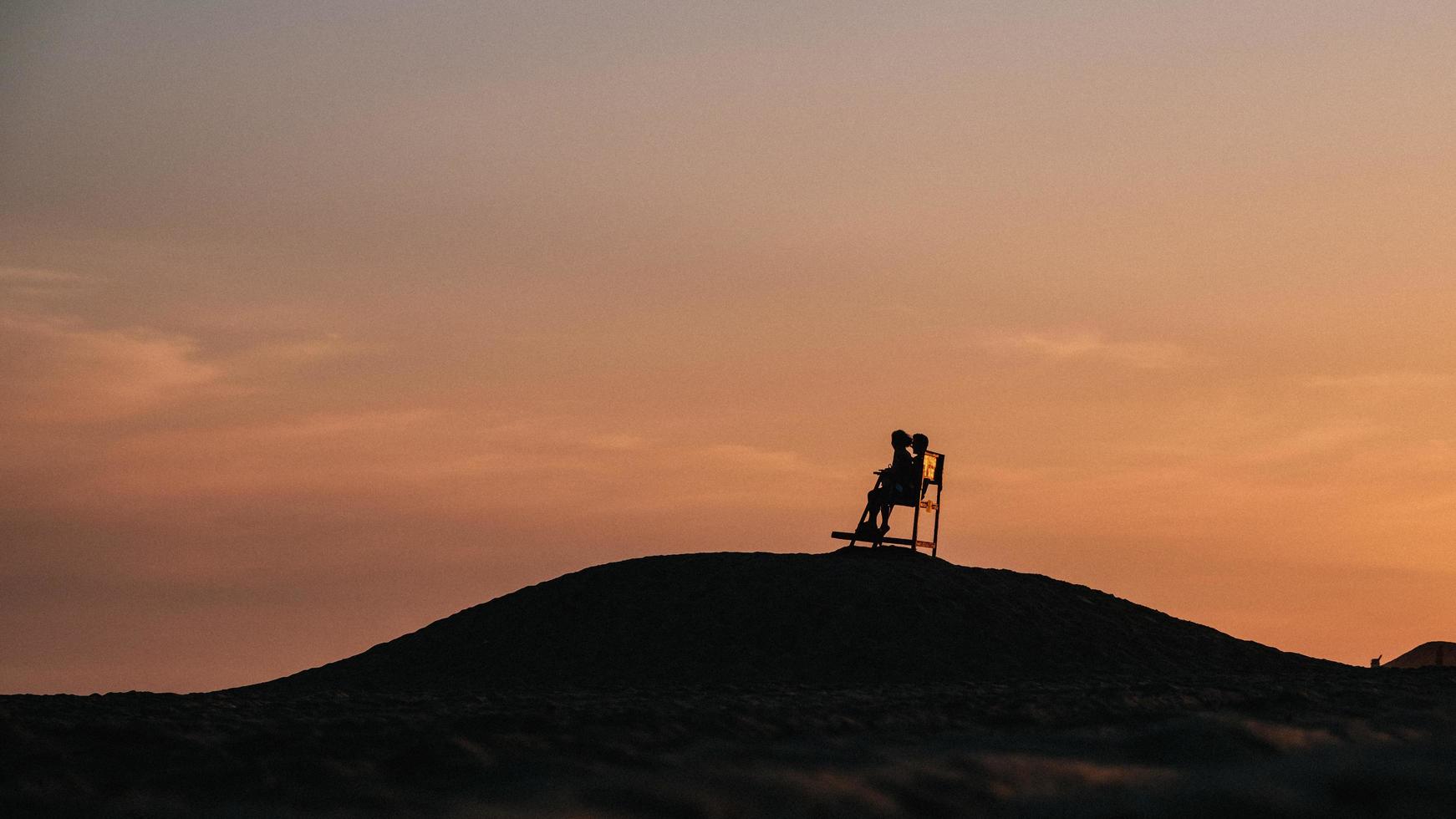 silhouette de 2 personnes debout au sommet de la montagne pendant le coucher du soleil photo