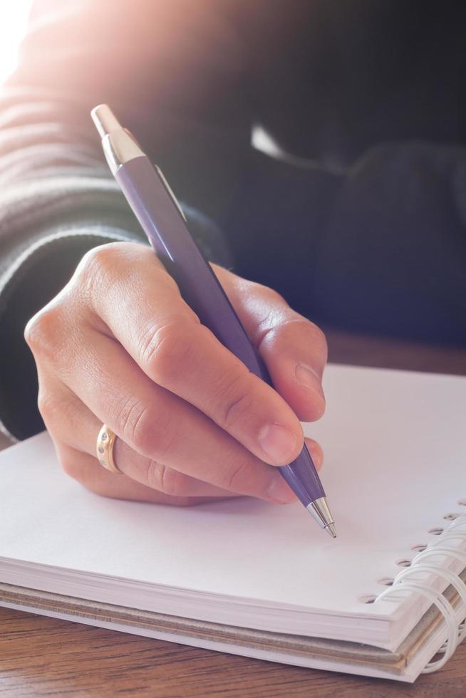 personne qui écrit dans un cahier sur une table photo