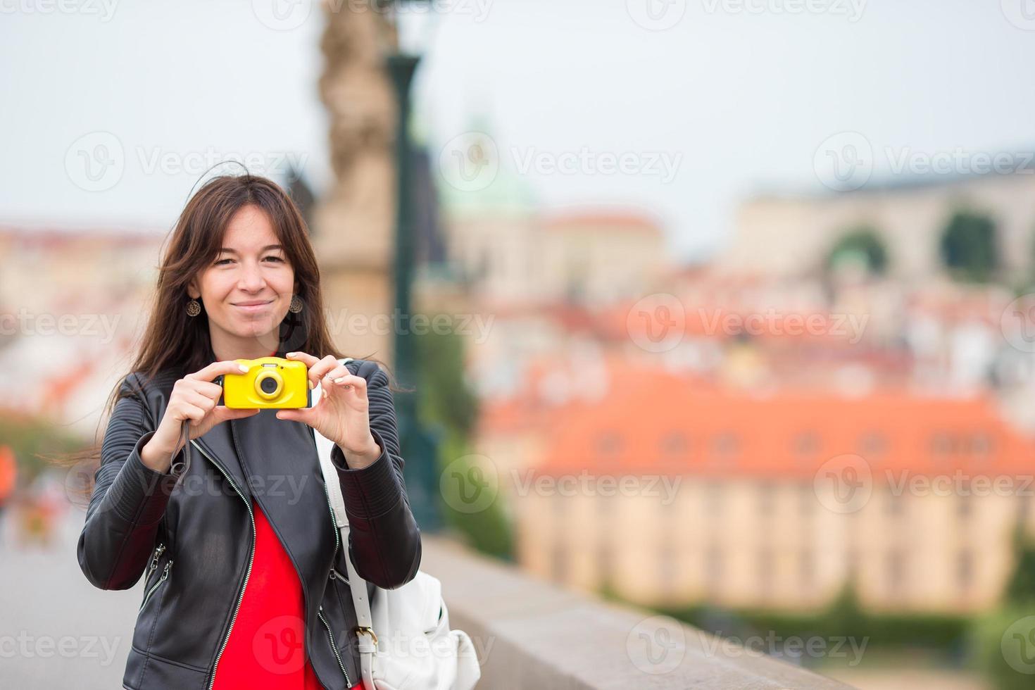 heureuse jeune femme dans une ville européenne sur le célèbre pont. Touriste caucasien prendre une photo par son appareil photo à Prague