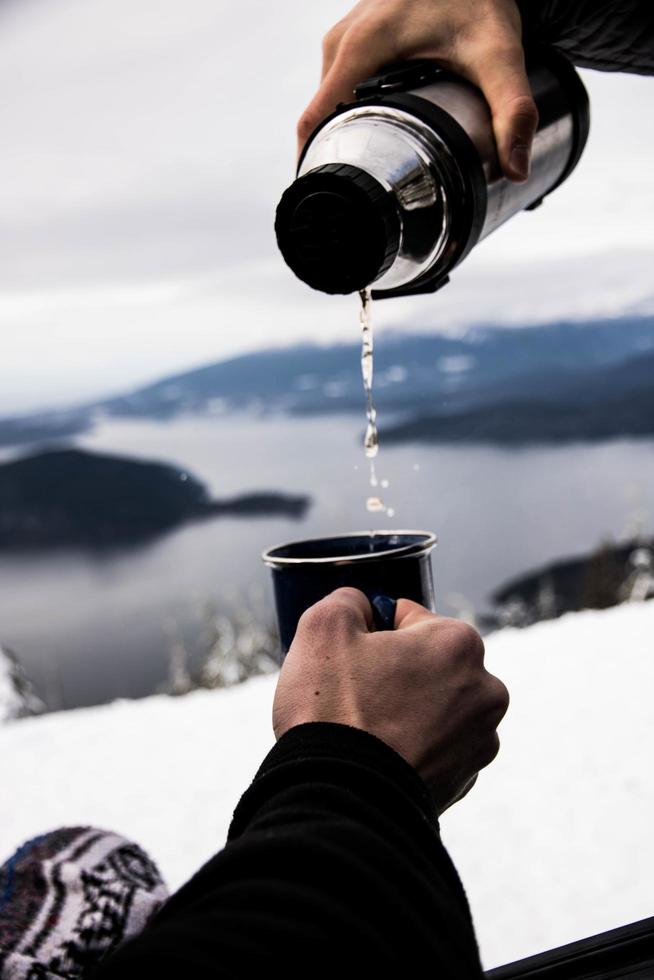 Personne versant de l'eau dans une tasse en céramique noire photo