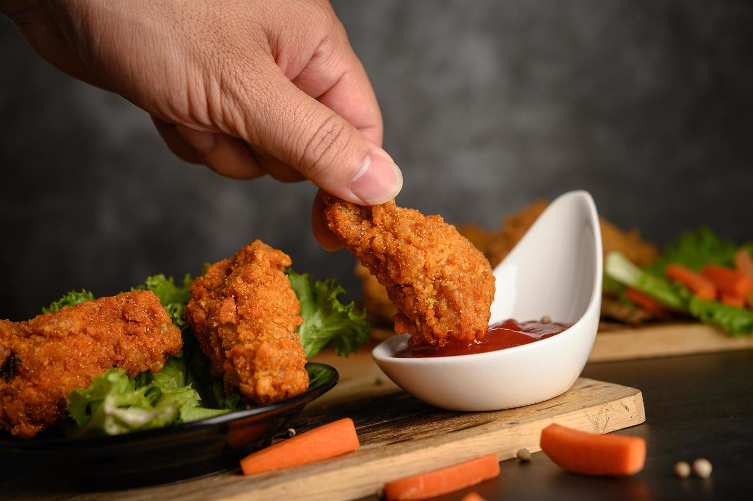 tremper à la main le poulet frit croustillant dans la sauce photo