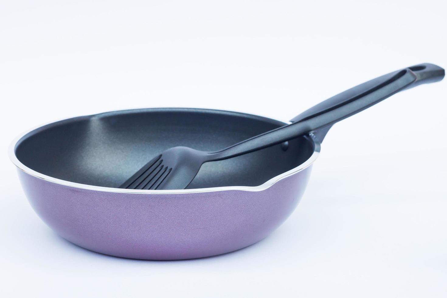 Poêle à frire violette avec une spatule sur fond blanc photo