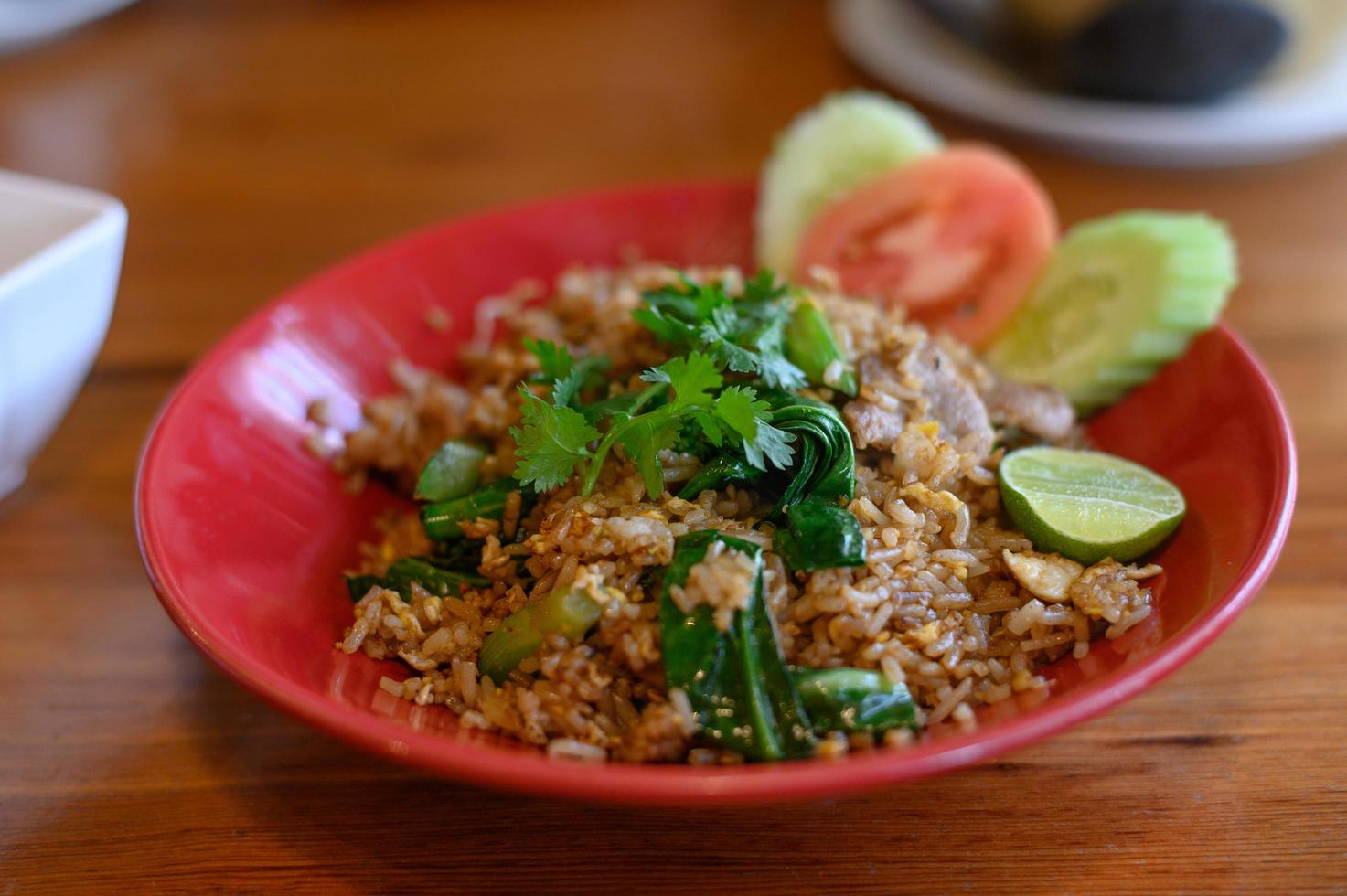 Riz frit au porc qui est sur l'assiette, avec un demi-citron sur la table en bois photo