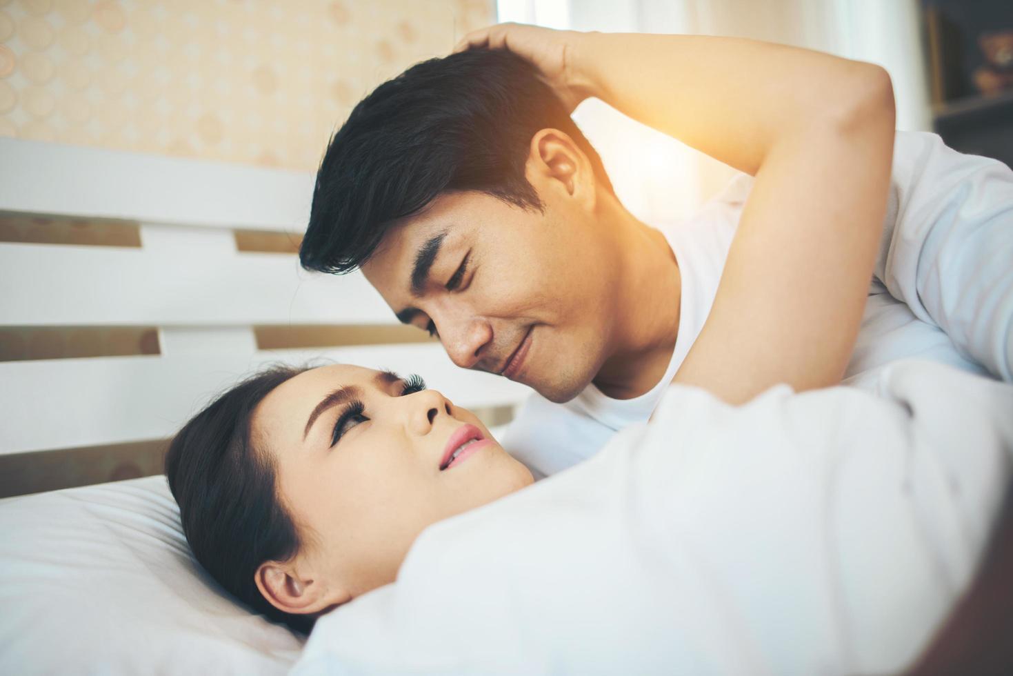 couple heureux allongé ensemble dans leur lit photo