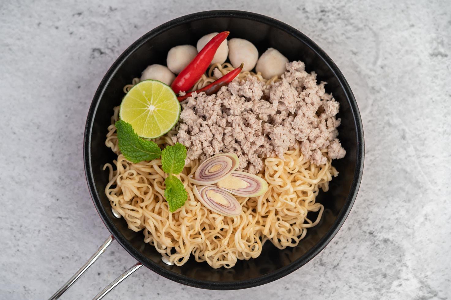 porc haché dans une poêle avec de la lime, des piments et des boulettes de viande photo