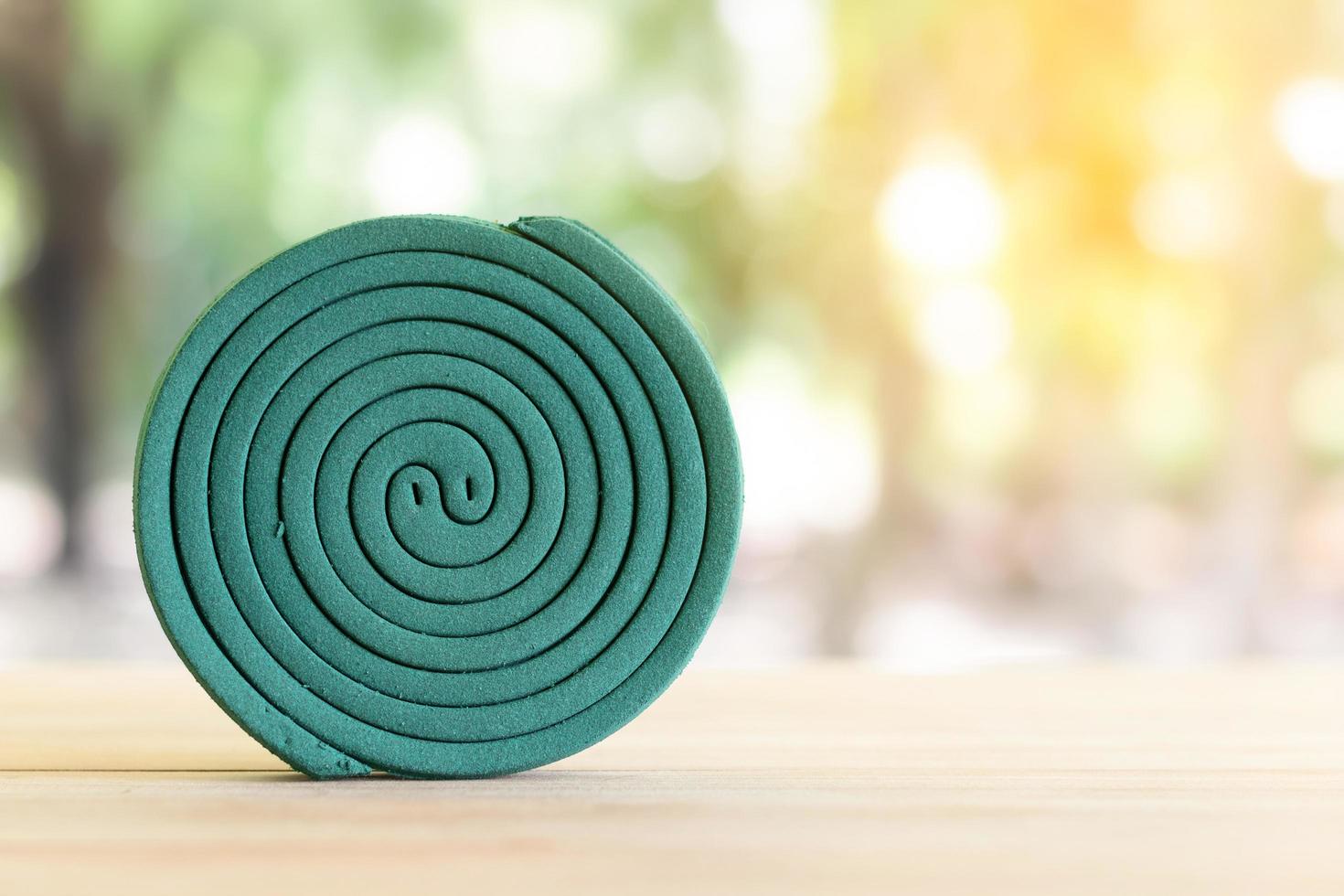 anti-moustique vert sur table en bois avec lumière floue verte. photo