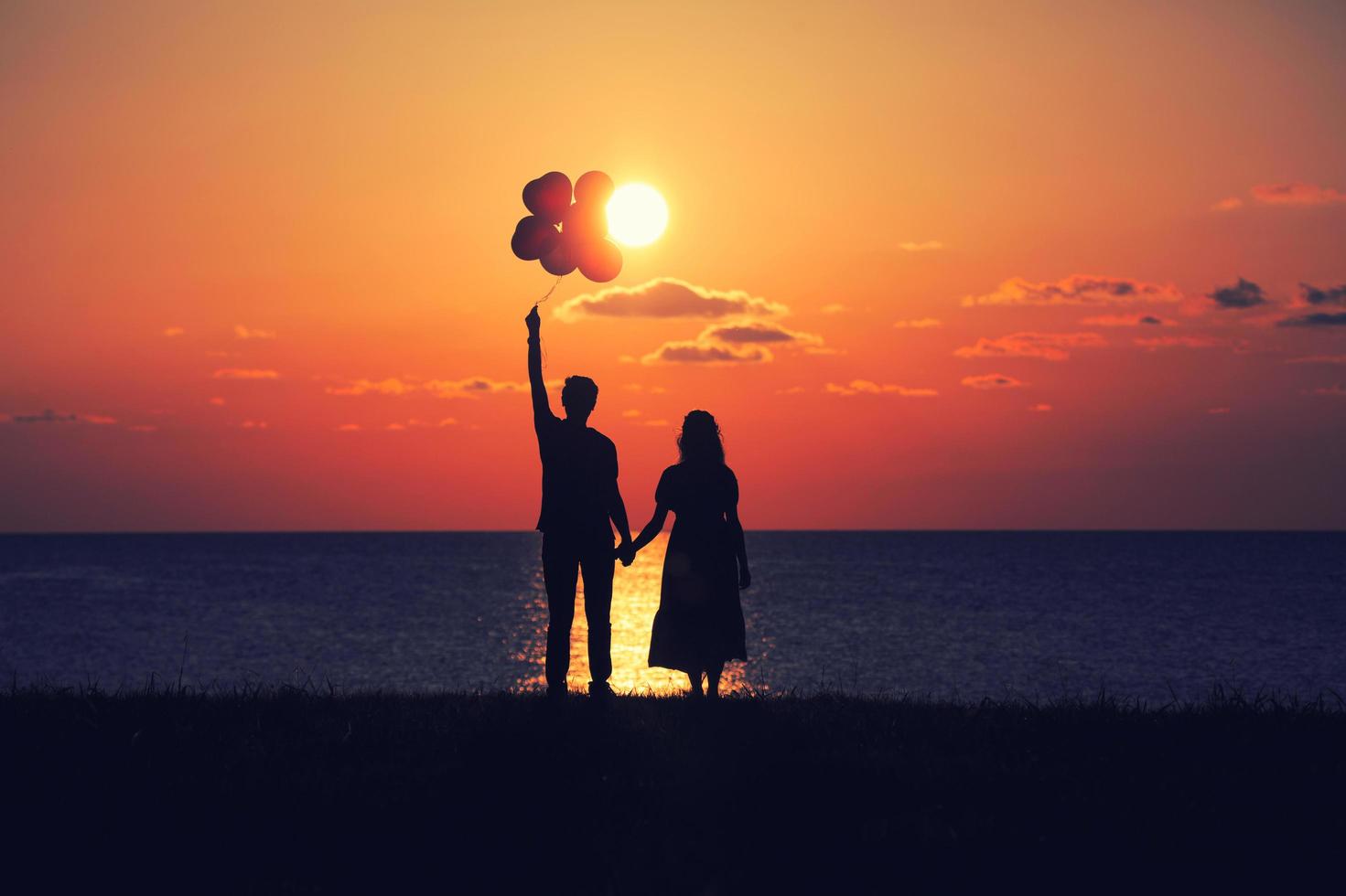 les amoureux regardant le coucher du soleil avec des ballons photo