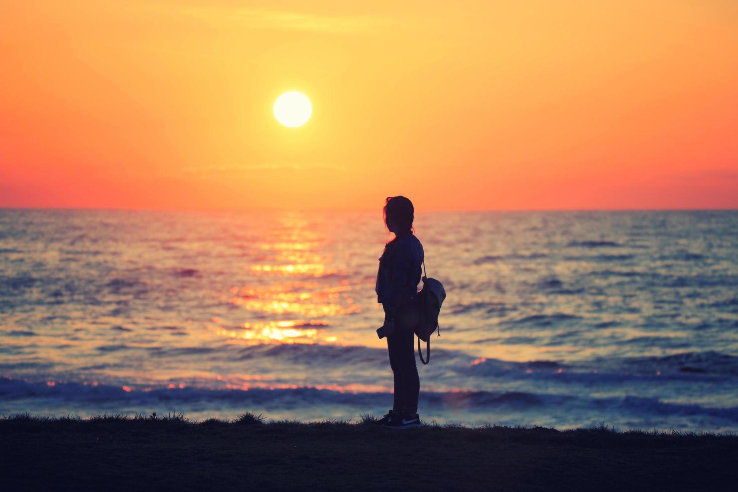 une fille regardant le coucher du soleil photo