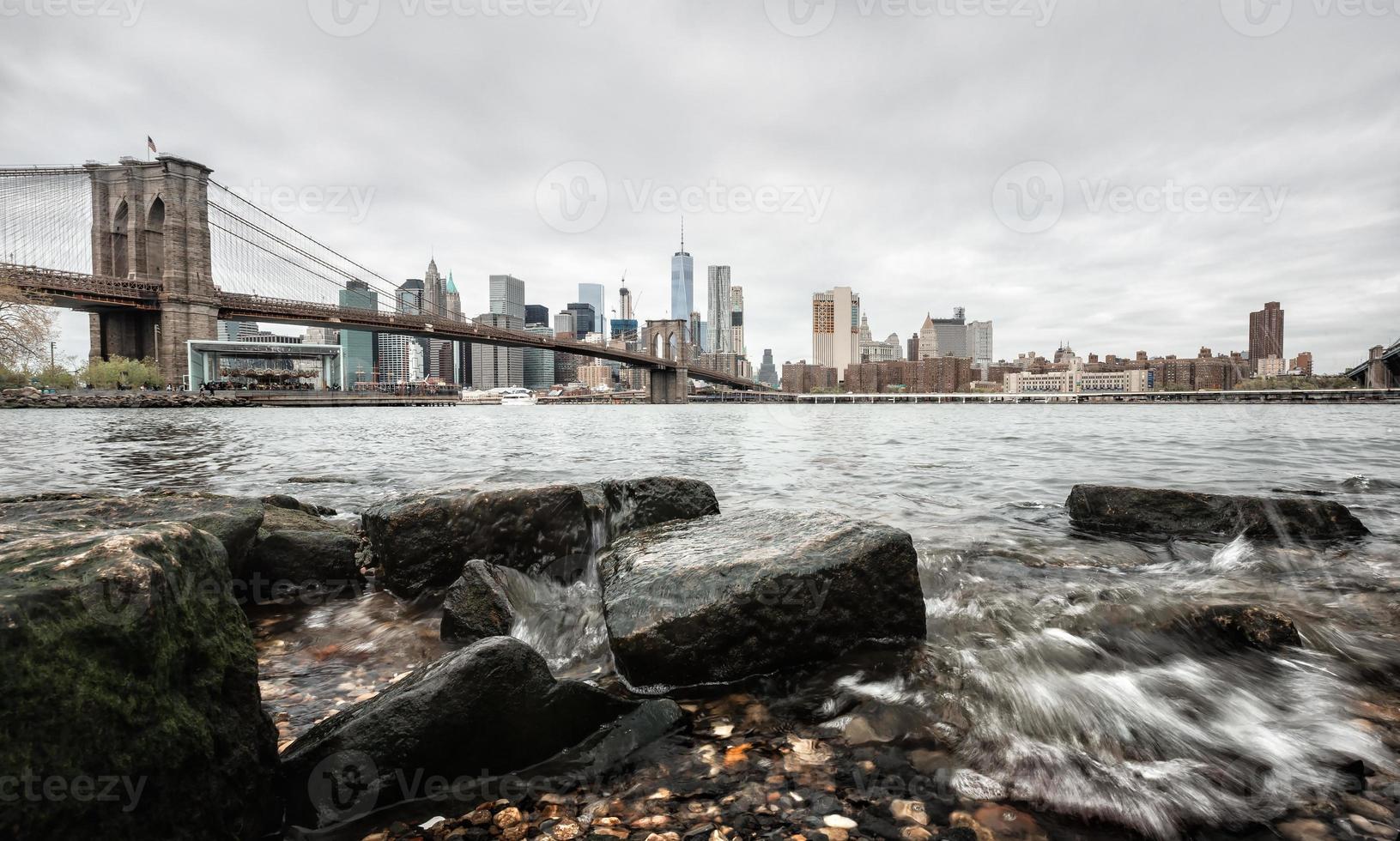 Pont de Brooklyn avec des rochers sur la rive de l'East River photo