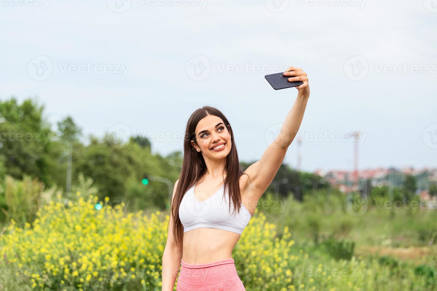 belle jeune femme courant dans la course de la ville en prenant un selfie, jeune femme faisant du selfie tout en faisant des exercices de fitness photo