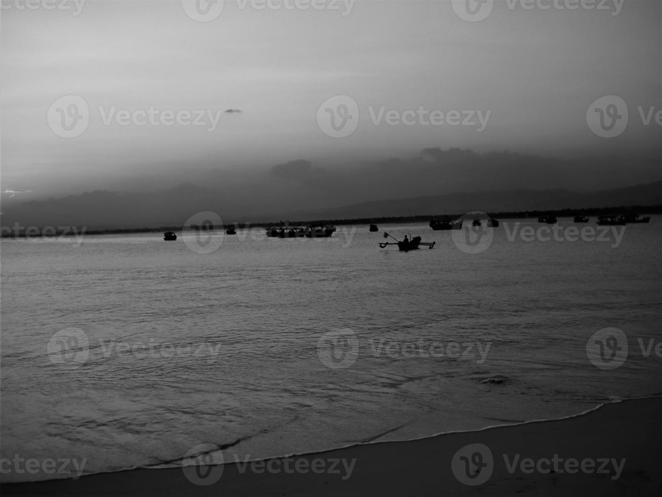 bateau de pêche sur la plage au coucher du soleil. noir et blanc. photo