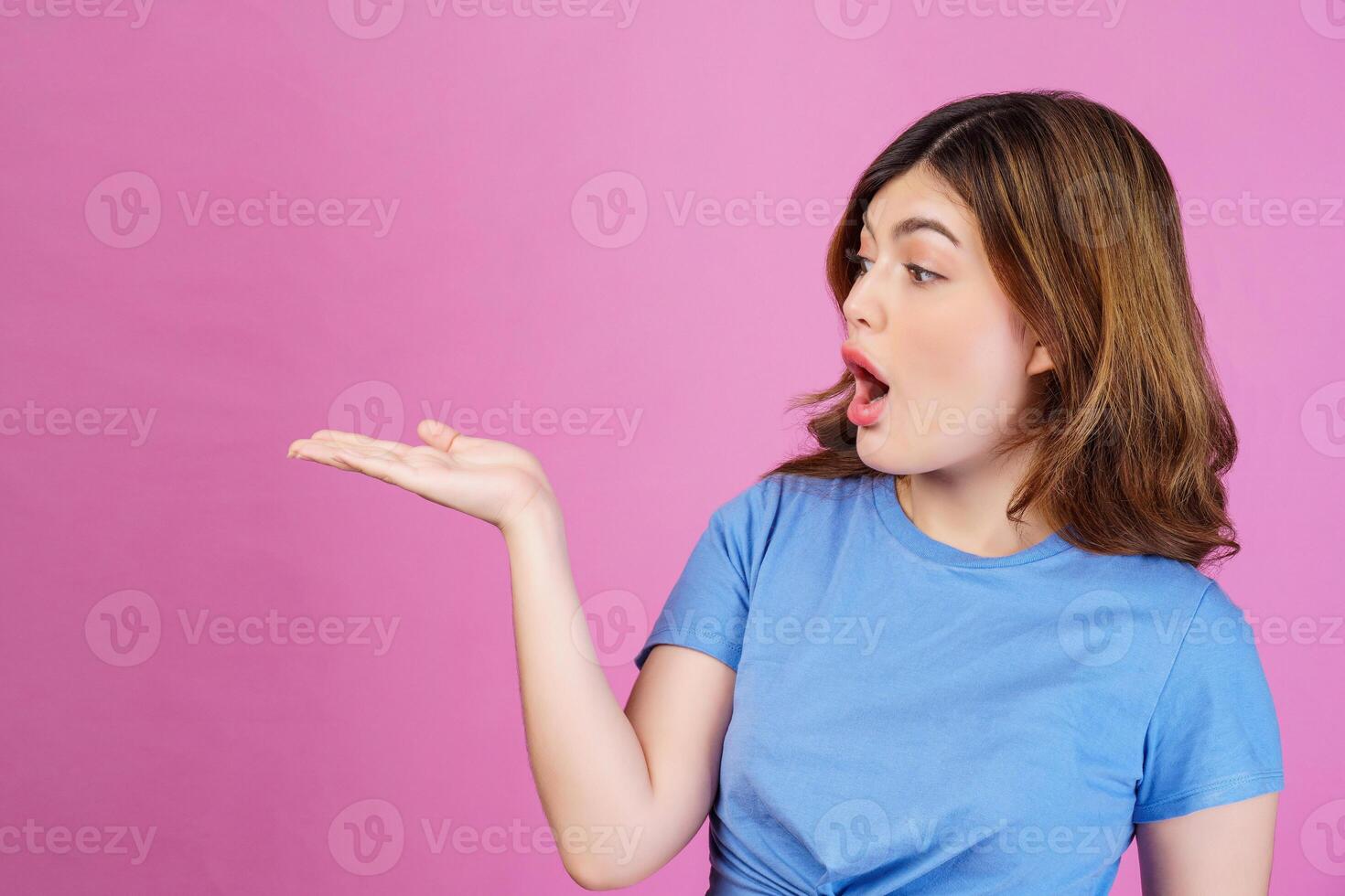 portrait d'une jeune femme excitée portant un t-shirt décontracté tenir la main démontrer l'offre d'annonces promotionnelles isolées sur fond rose photo