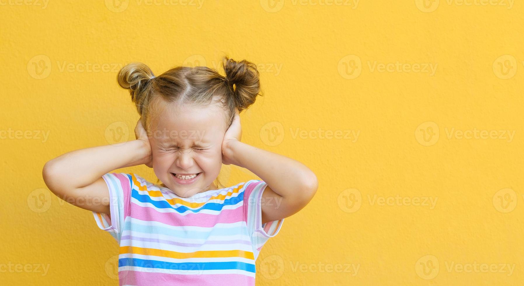 petite fille malheureuse enfant fermer les yeux et les oreilles étant ennuyé par le bruit voulant le silence et l'atmosphère calme, isolé sur fond de studio jaune photo