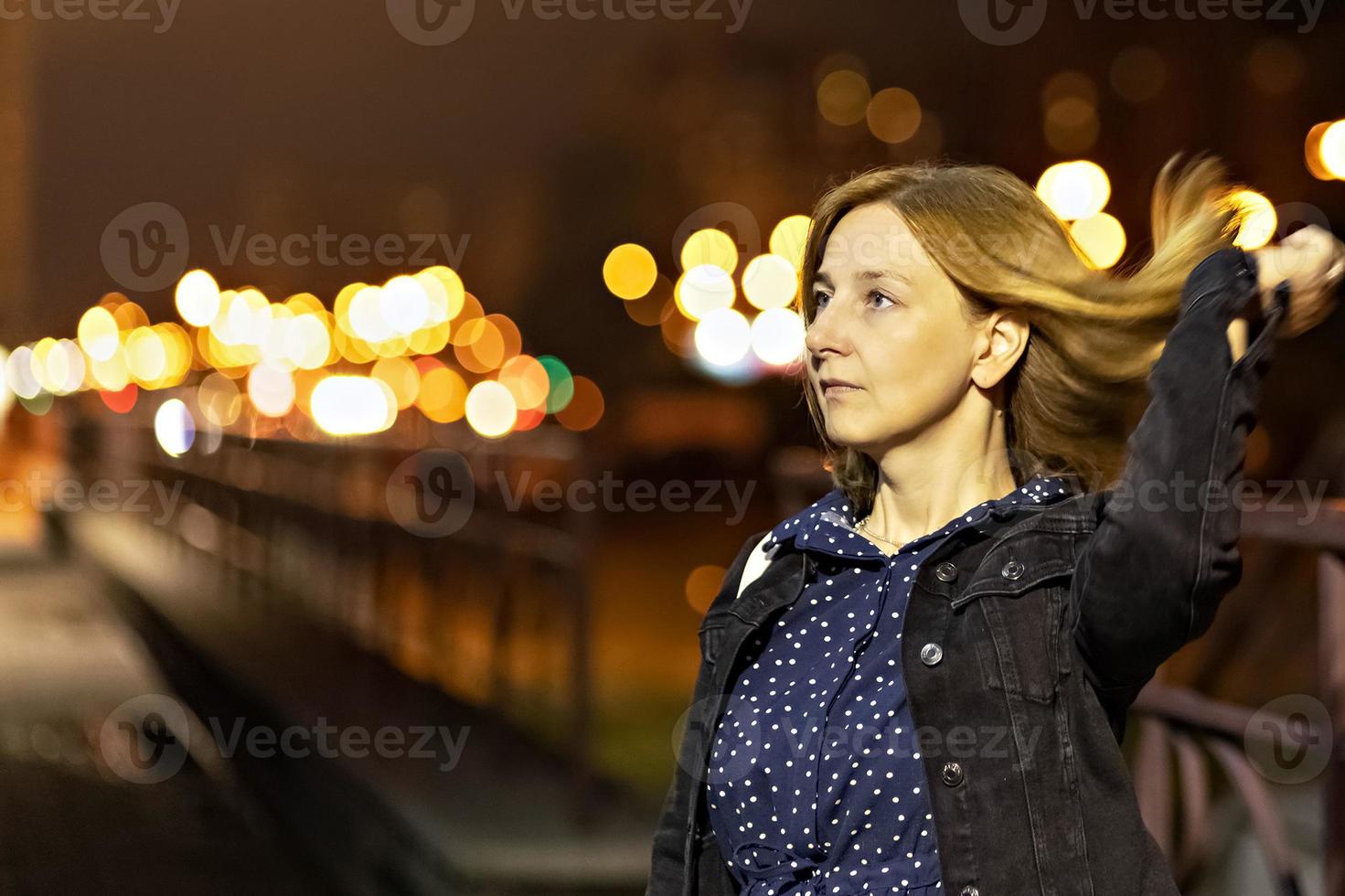 portrait d'une jeune femme dans une ville nocturne un soir d'été. lumières de la ville photo