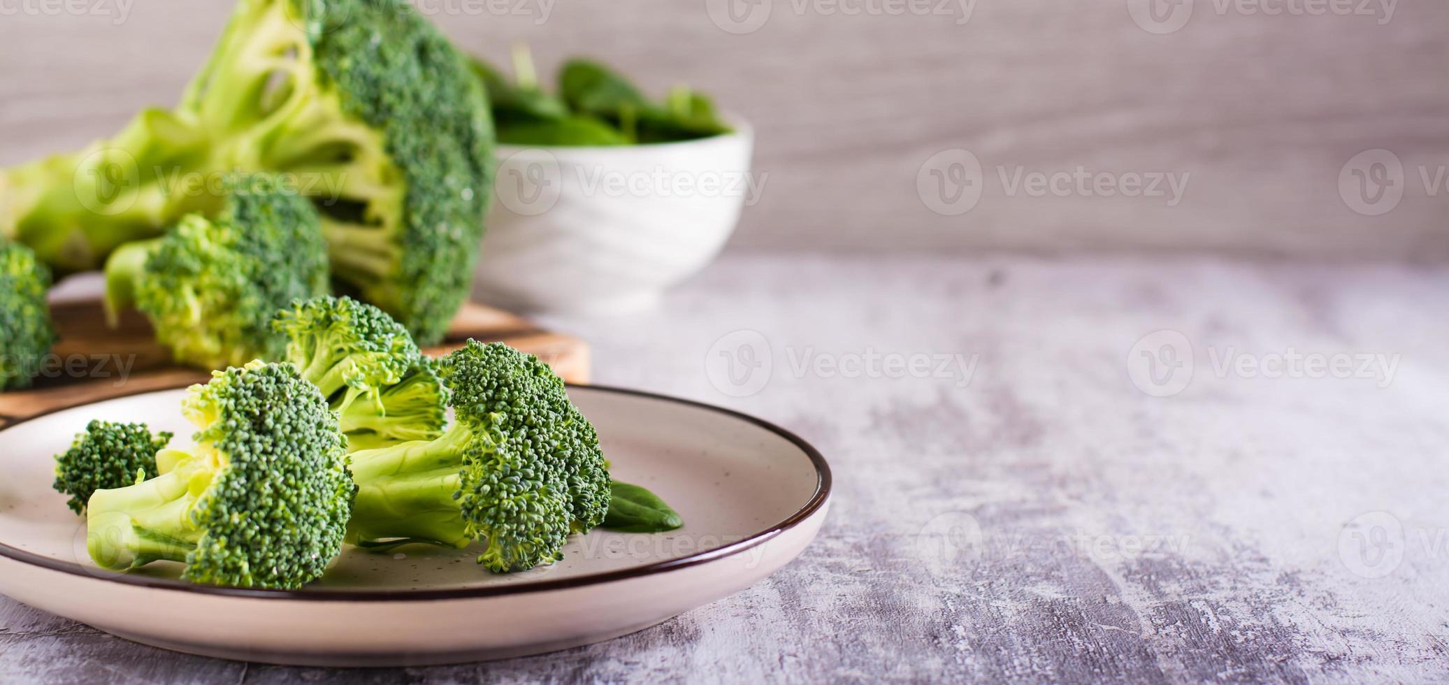 feuilles de brocoli et d'épinards frais sur une assiette sur la table. aliments sains, aliments verts. bannière internet photo