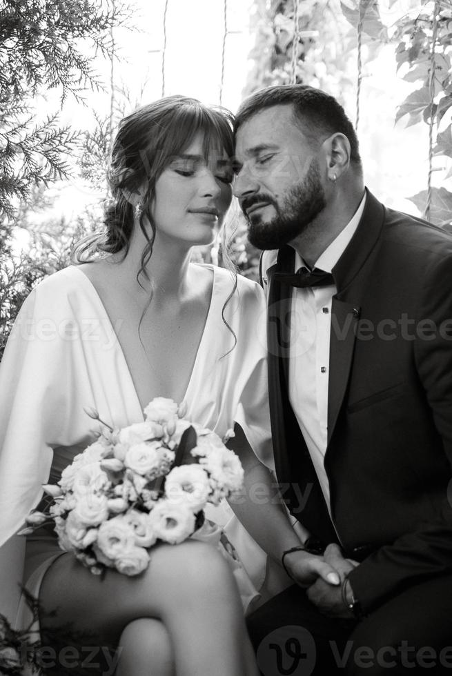 mariée en robe blanche avec un bouquet et le marié en costume bleu photo