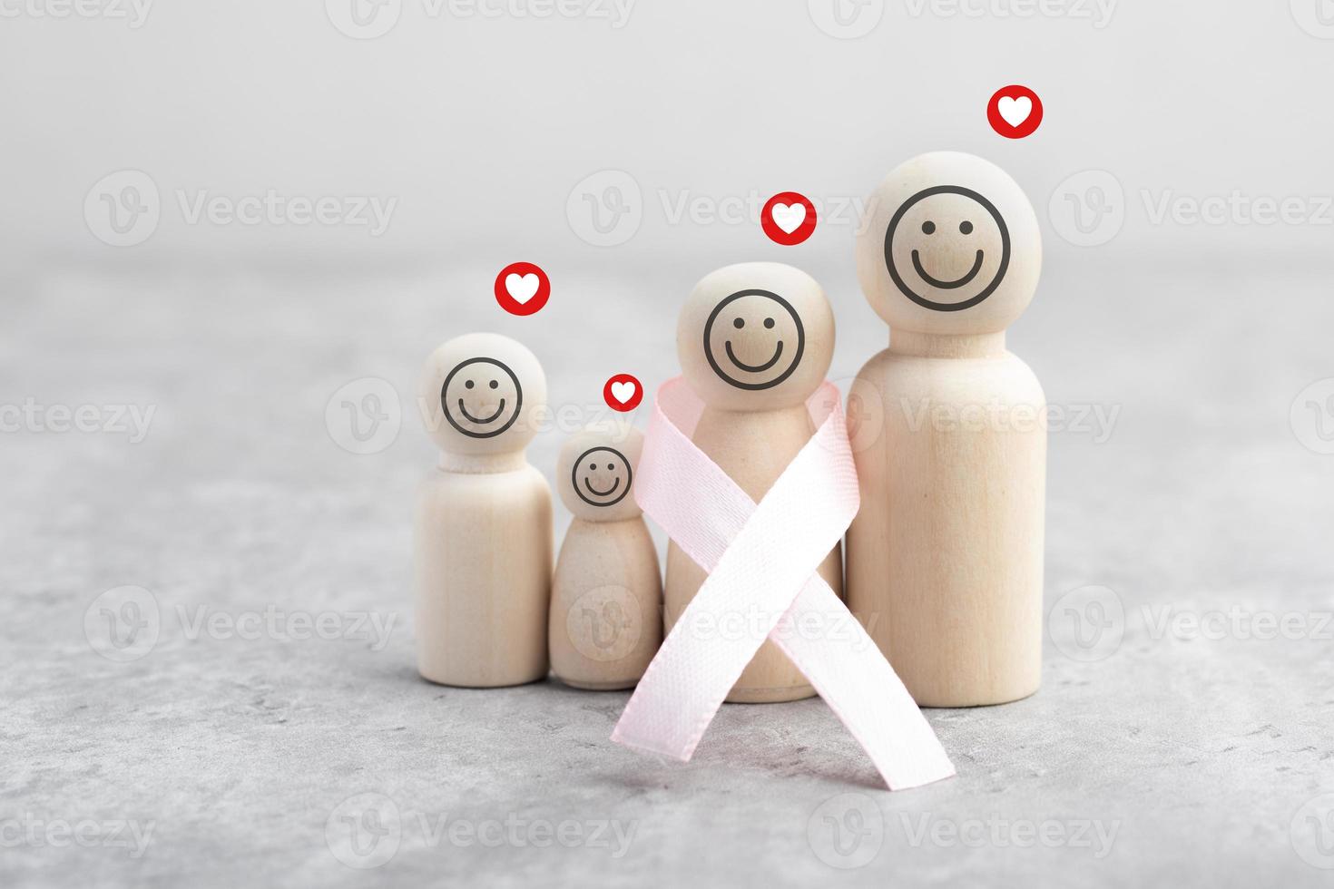 figurine en bois familiale et ruban rose. concept de traitement du cancer. photo