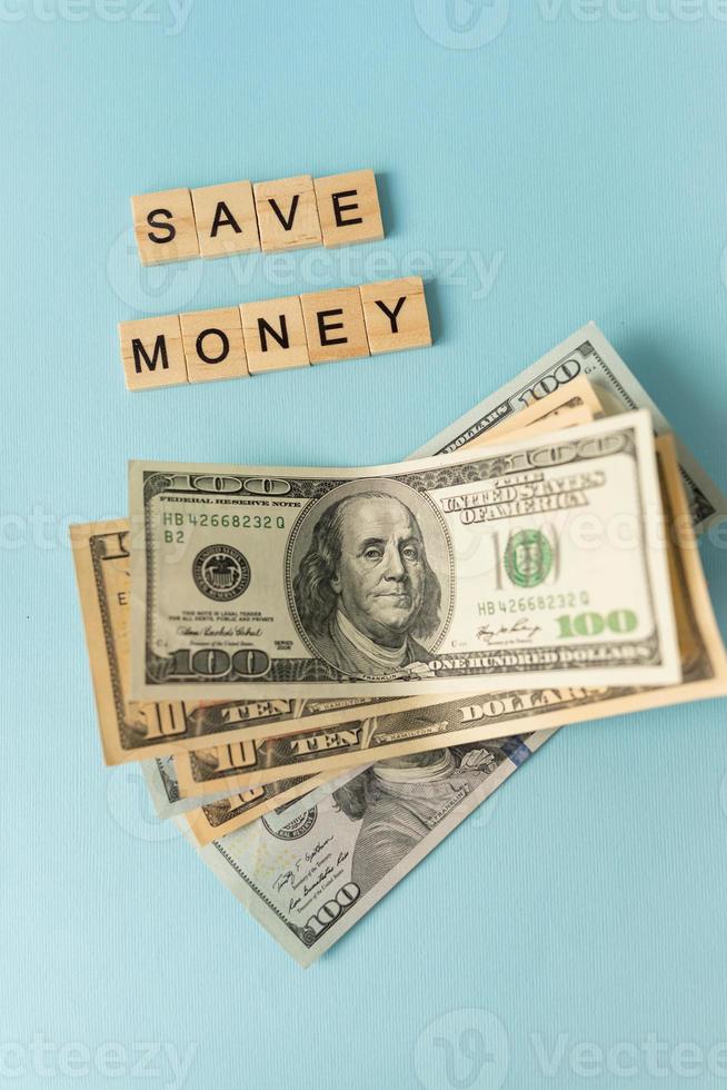 argent en monnaie internationale, les dollars se trouvent sur un fond bleu. inscription économiser de l'argent. photo