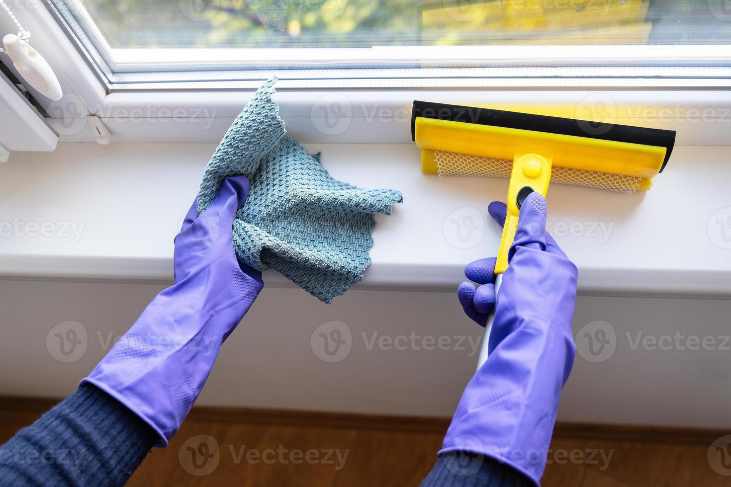 concept de nettoyage et de nettoyage. une jeune fille en gants violets tient un chiffon et une vadrouille pour nettoyer les vitres. photo