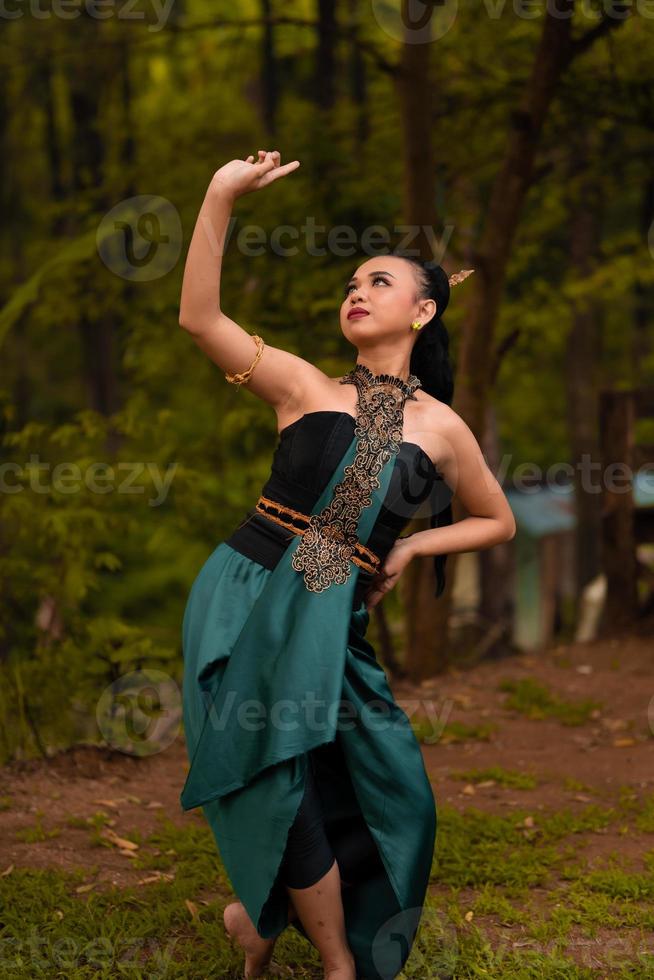 les femmes balinaises lèvent les mains en l'air en dansant en costumes verts tout en se produisant au festival photo