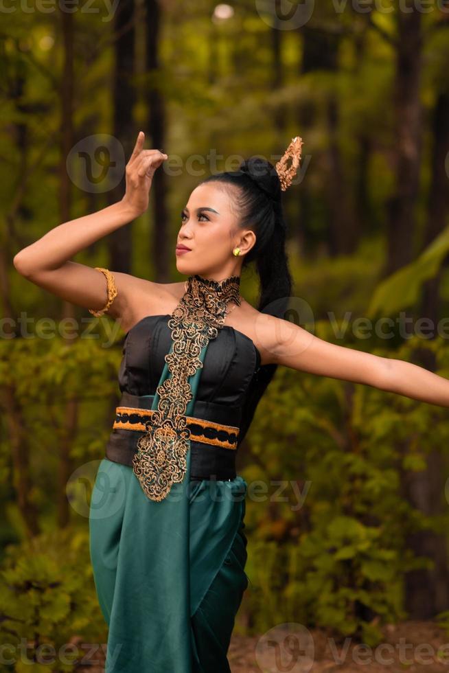 belles danseuses indonésiennes avec des costumes verts traditionnels et des cheveux noirs attachés posant à l'intérieur de la forêt photo