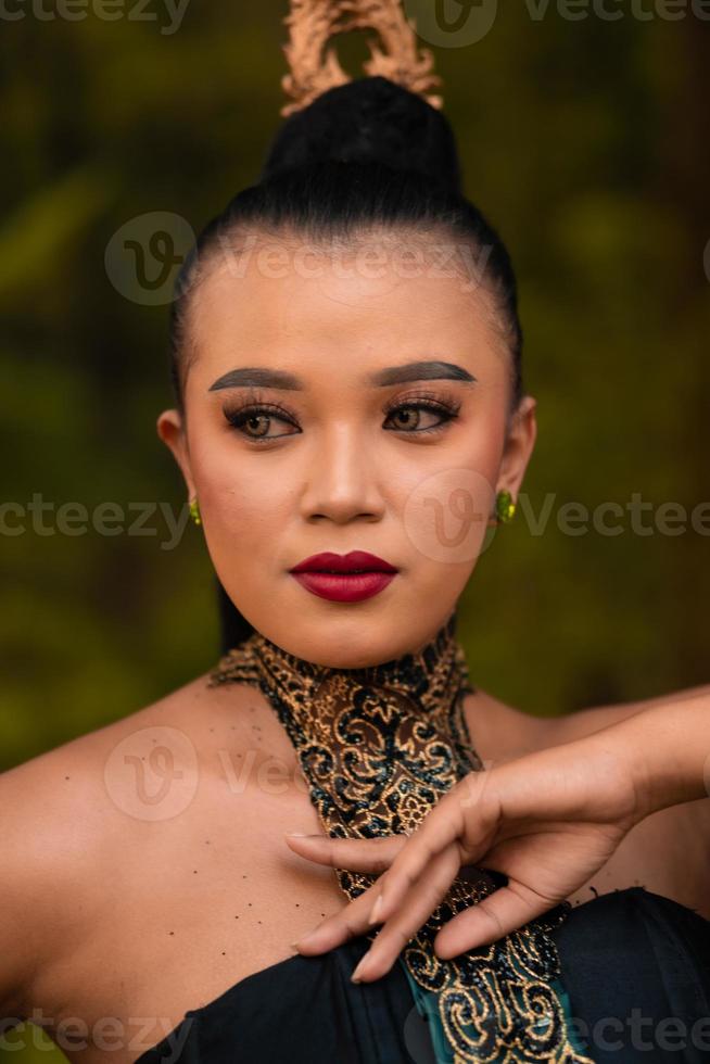 portrait d'une femme asiatique maquillée et lèvres rouges tout en portant un collier doré et des accessoires dorés sur ses cheveux noirs en position debout photo