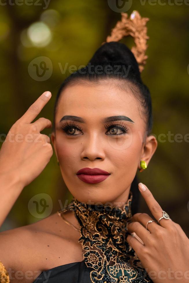 belle femme asiatique avec du maquillage et des cheveux noirs attachés portant un bijou noir avant de danser sur la scène photo