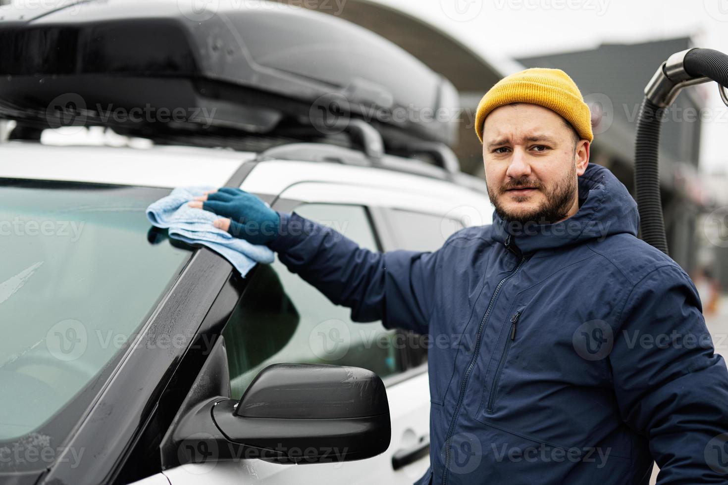 l'homme essuie la voiture suv américaine avec un chiffon en microfibre  après le lavage par temps froid. 21140545 Photo de stock chez Vecteezy