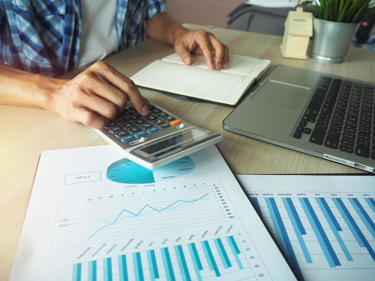 main d'homme appuyant sur la calculatrice calculant les informations sur son bureau. photo