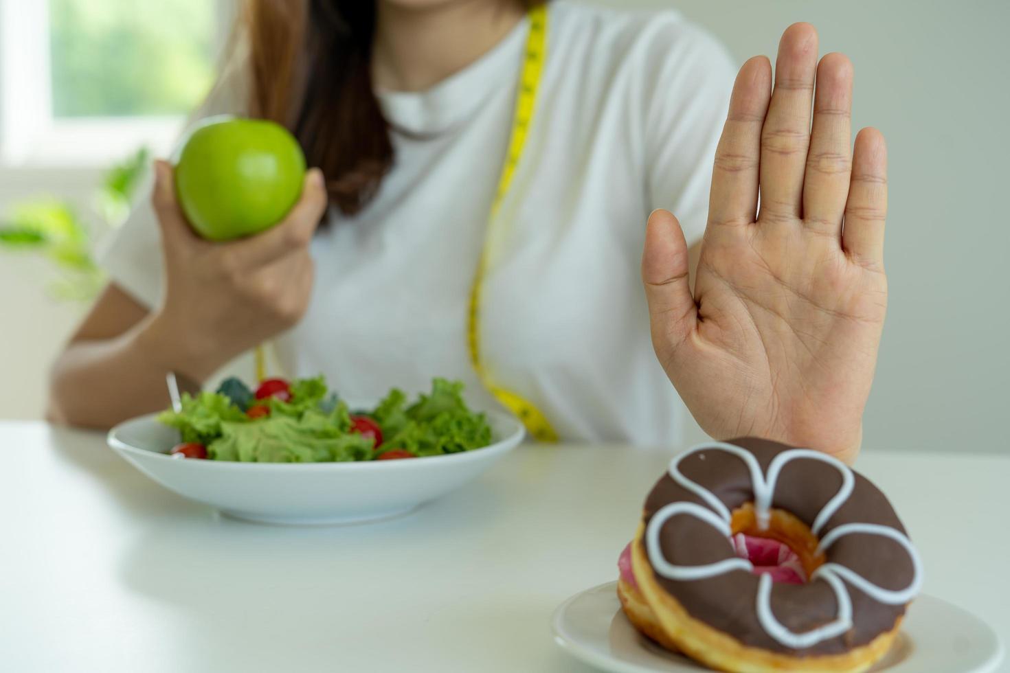 les femmes refusent de manger des beignets et choisissent de manger des salades avec des fruits. des femmes en bonne santé et des corps forts. notion de régime photo