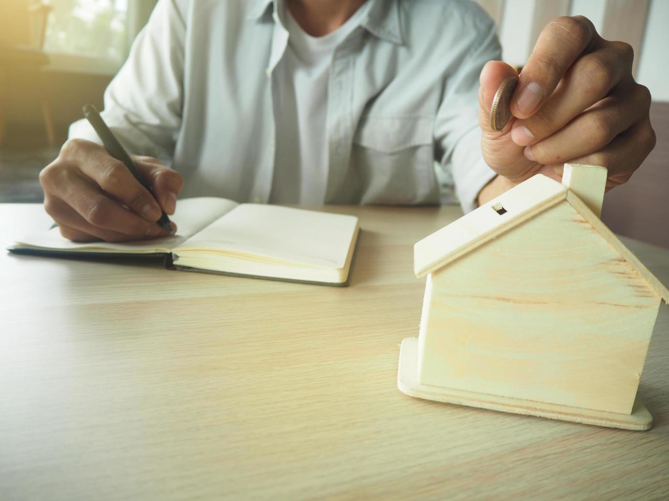 le concept d'économie d'argent. économies sur les dépenses domestiques les mains des hommes mettent des pièces dans une tirelire. et les données d'utilisation à domicile sont enregistrées dans le livre. photo