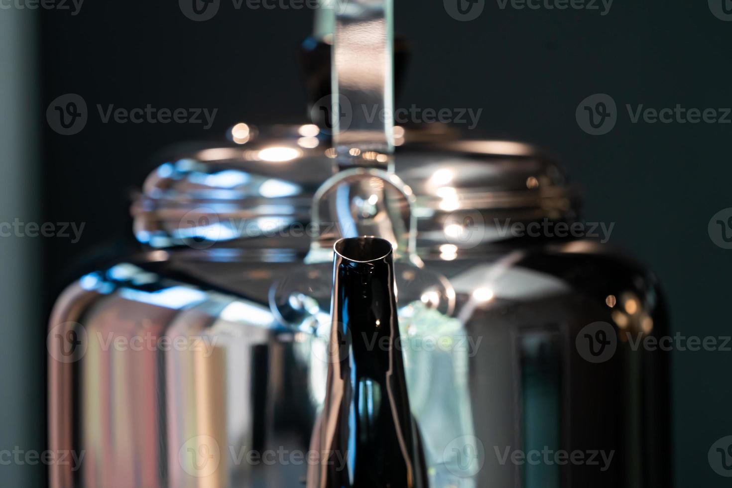 corbeau d'eau en acier inoxydable ou théière vintage sur cuisinière électronique sur fond bleu foncé moderne. photo