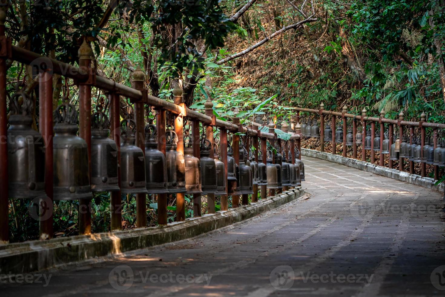 passerelle avec les cloches de bronze en métal autour et à côté de celle-ci dans l'environnement de la jungle, au temple wat phra that doi tung, province de chiang rai, au nord de la thaïlande. photo