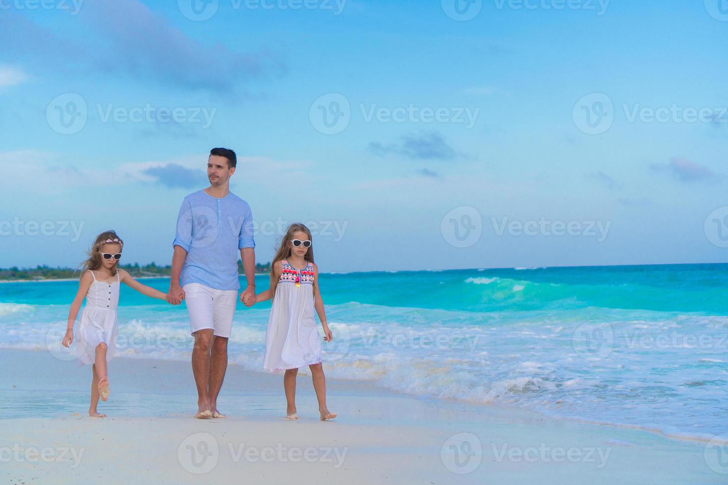 famille de papa et d'enfants marchant sur une plage tropicale blanche sur l'île des caraïbes photo