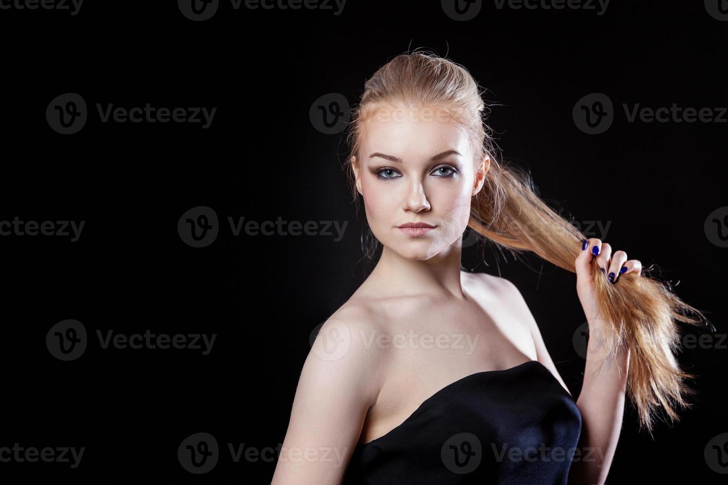 fille de modèle de mode de beauté avec une longue coiffure en queue de cheval de cheveux lisses et sains sur fond noir. souriante jolie femme regardant la caméra. parfait portrait de peau fraîche. concept de soins de la jeunesse et de la peau. photo