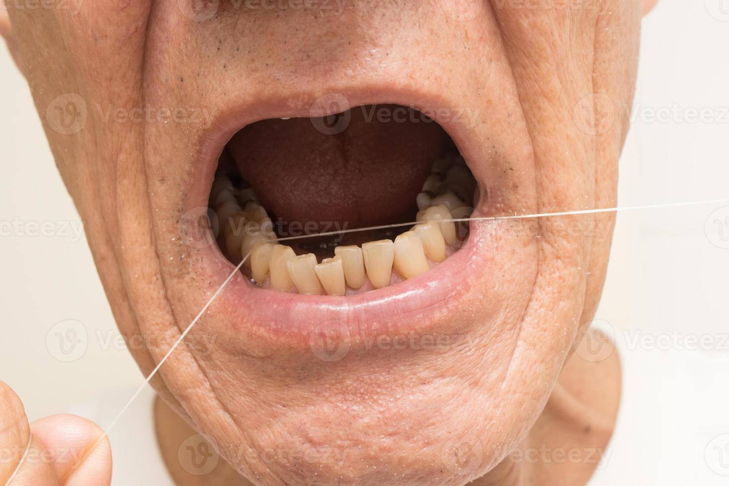 gros plan d'un homme plus âgé passant la soie dentaire avec du fil dentaire photo