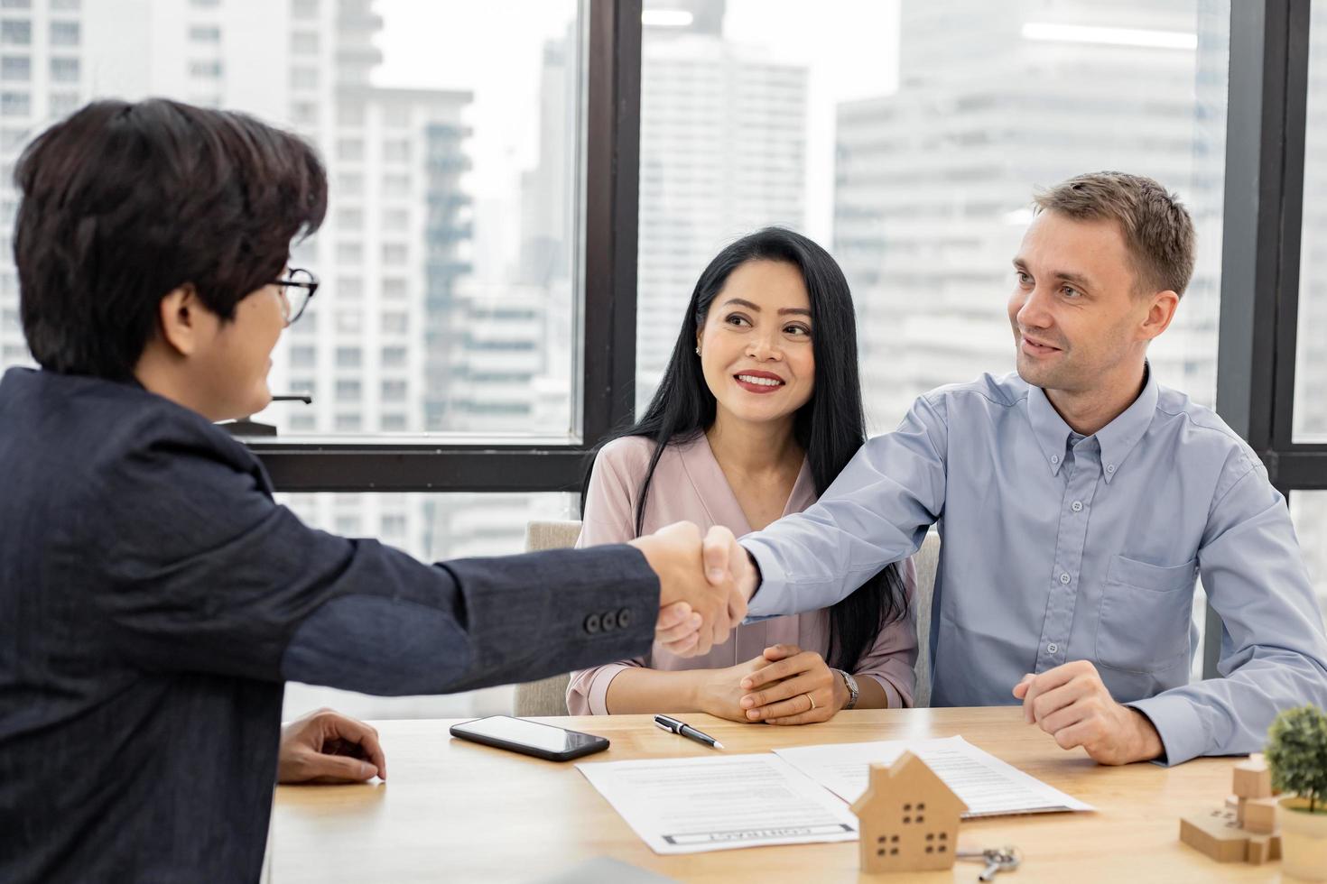 couple se serrant la main comme accord réussi dans le contrat de transaction de la maison avec le courtier. photo