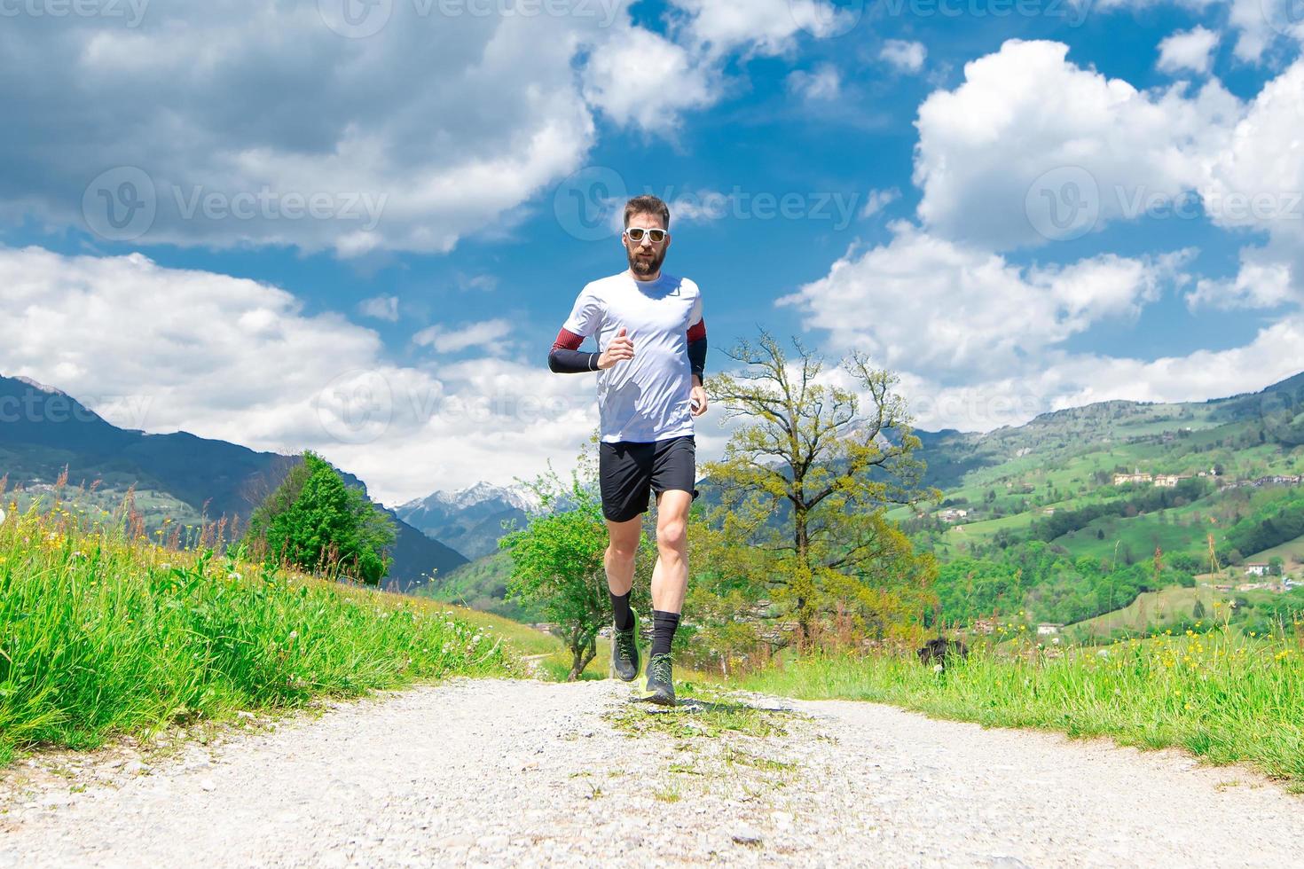 Coureur de marathon s'entraîne dans un chemin de terre de montagne photo