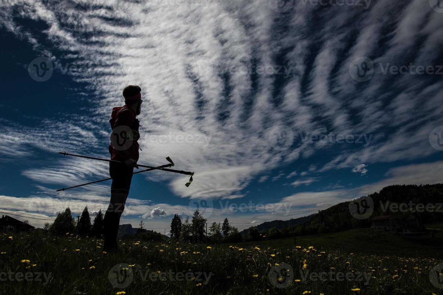 un randonneur avec des bâtons au crépuscule arrête de regarder le paysage photo