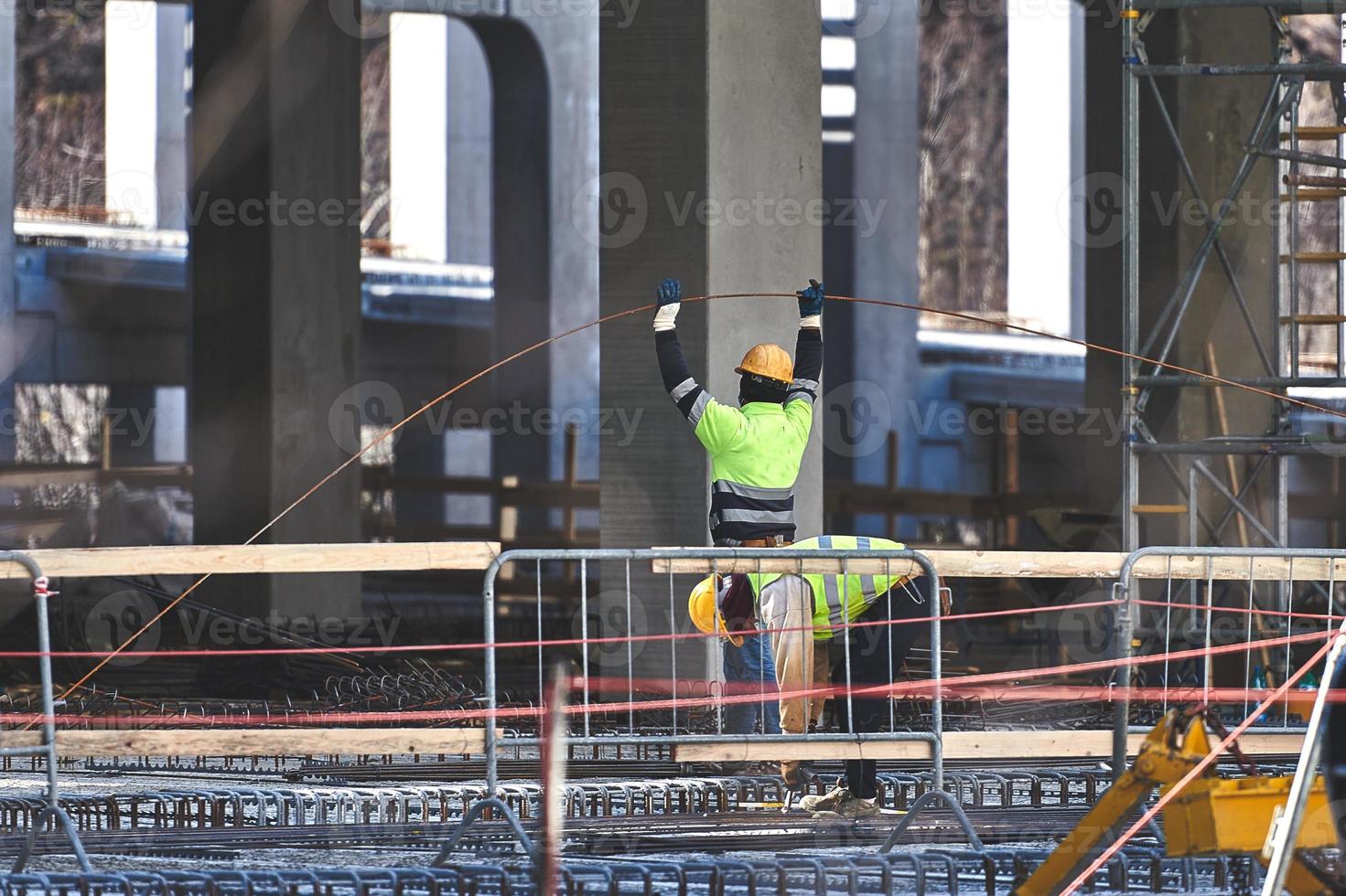 les ouvriers du bâtiment sur le chantier travaillent avec des armatures en béton photo