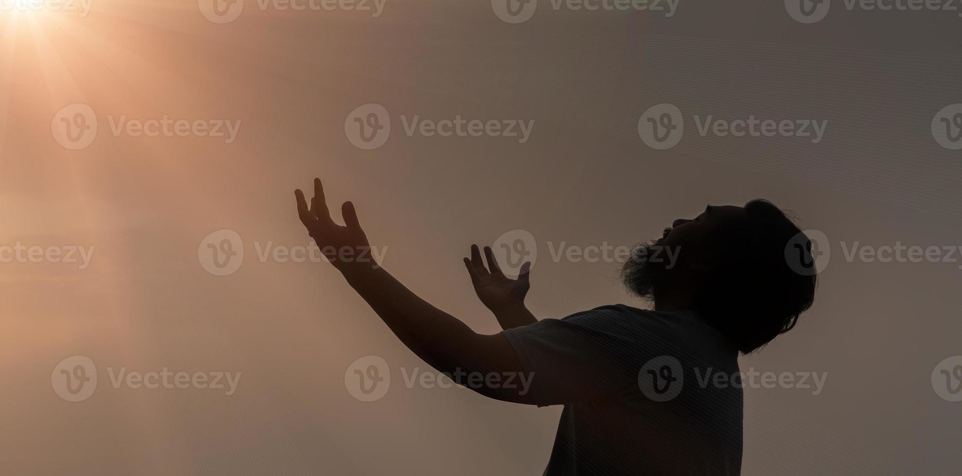 adorer avec la foi du concept chrétien. la prière spirituelle remet le soleil avec un beau fond de coucher de soleil flou. le prédicateur prie Dieu le matin avec dévotion. l'homme chrétien a de l'espoir. photo