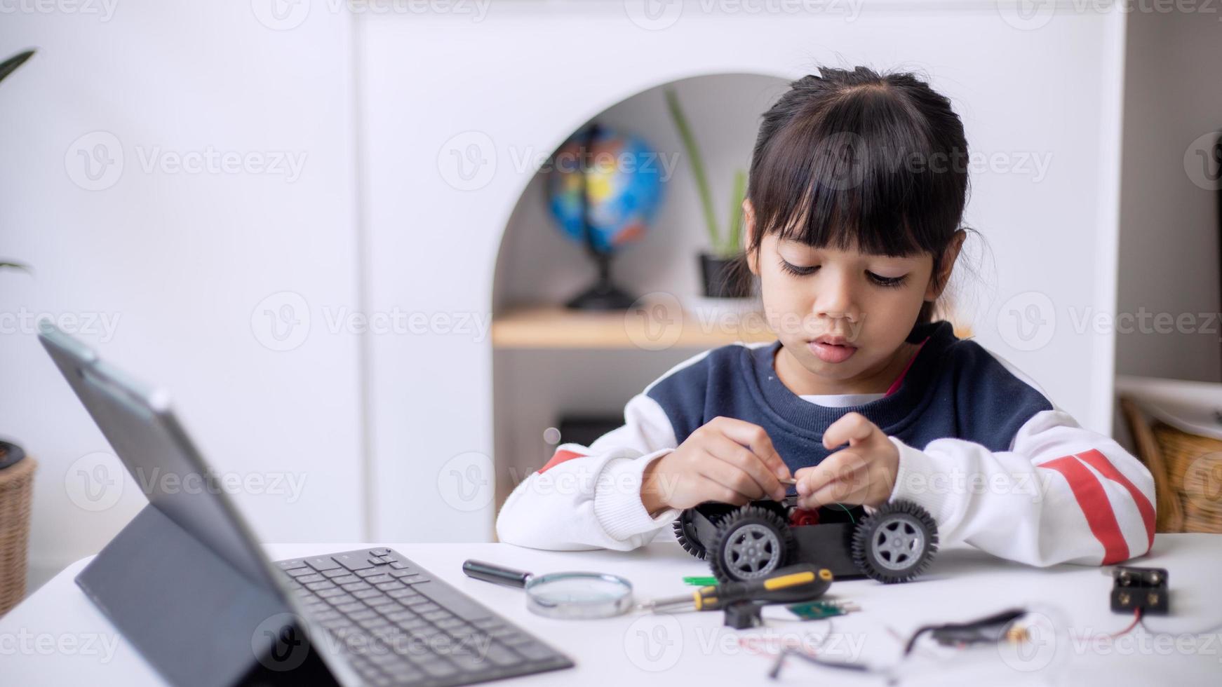 les étudiants asiatiques apprennent à la maison à coder des voitures robotisées et des câbles de cartes électroniques dans la tige, la vapeur, la technologie des sciences de l'ingénierie mathématique le code informatique dans la robotique pour le concept des enfants photo