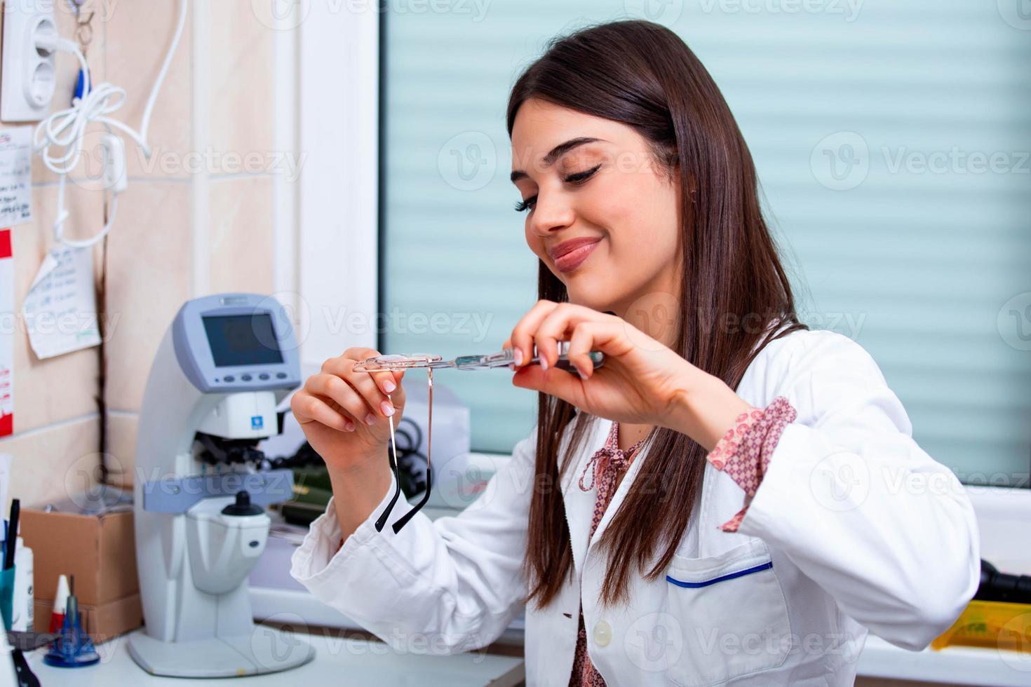 opticien réparant des lunettes avec un outil dans un magasin d'optique photo