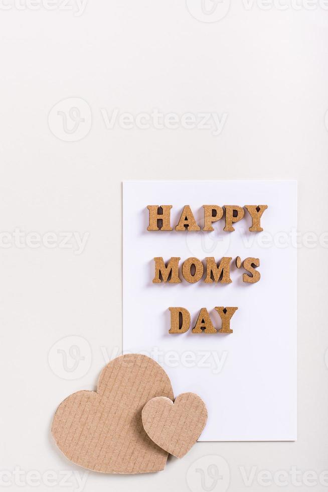 Bonne fête des mères. feuille de papier avec lettres et coeurs en carton sur fond clair. photo