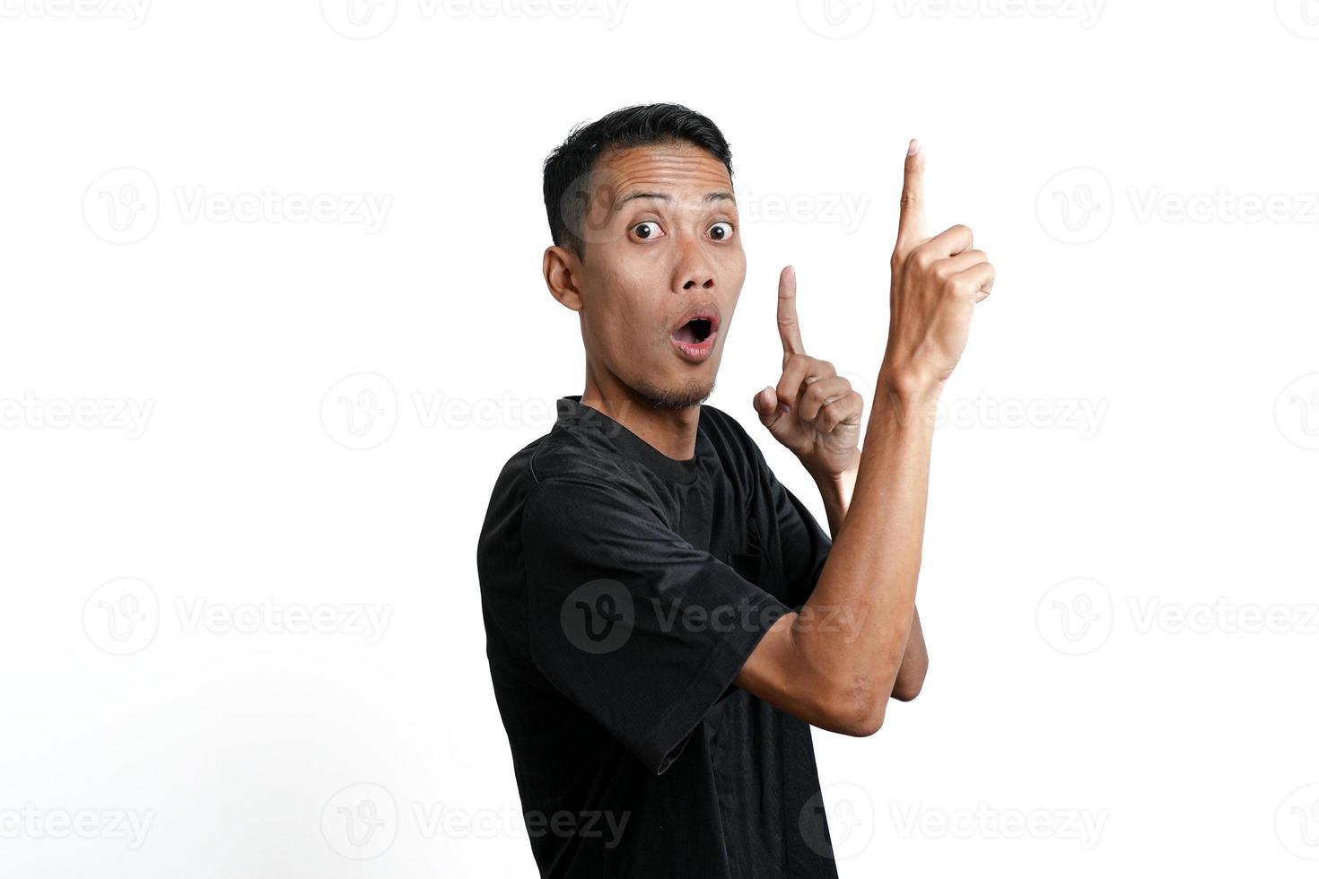 homme asiatique excité portant un t-shirt d'entraînement noir, pointant vers l'espace de copie. isolé sur fond blanc photo